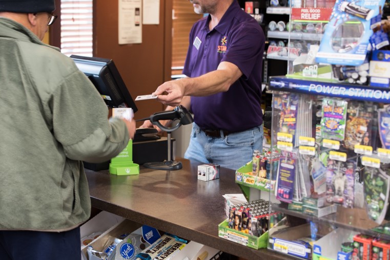 Image of cashier using a POS system that meets the needs to an example of basic needs to future proof your convenience store POS System